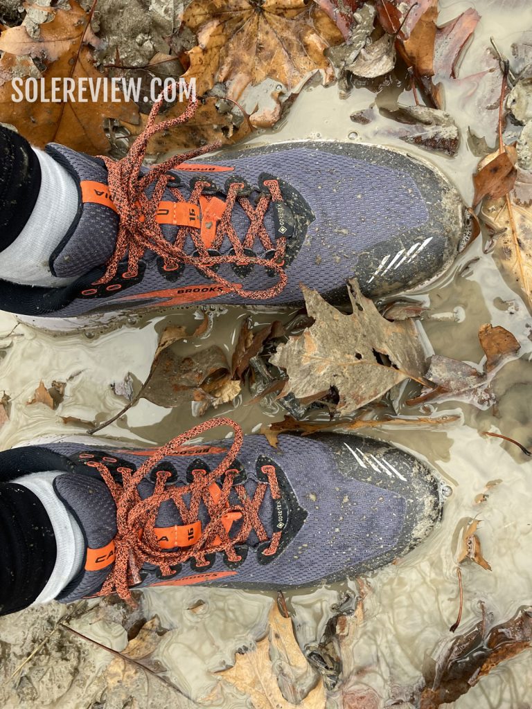 The Brooks Cascadia 16 Gore-Tex in a muddy puddle.