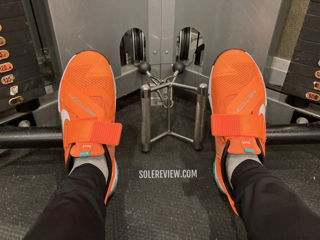 The Nike Metcon 7 Flyease on a weight rack.